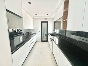 A modern kitchen with white cabinets, black countertops, and a built-in oven. - Dahlia Duplex au Coeur de La Marsa (La Marsa)