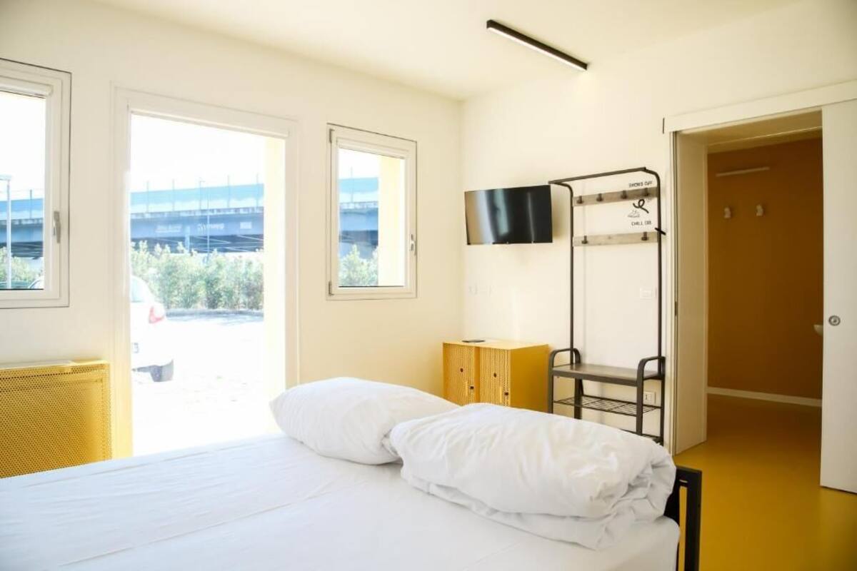 Une chambre d’hôtel équipée d’un lit, d’un téléviseur fixé au mur, d’un lit superposé et d’une porte donnant sur un espace extérieur.