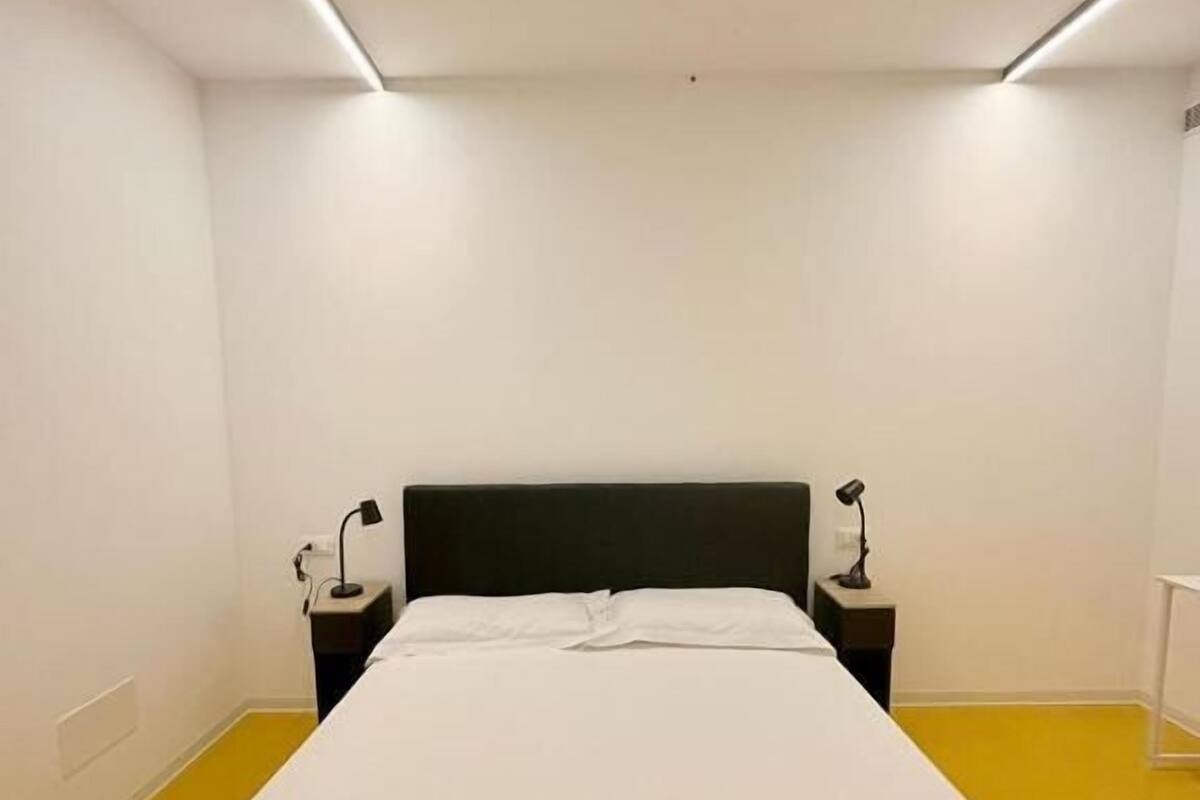 Une chambre à coucher avec un lit, deux tables de chevet et un sol jaune.