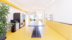 A modern interior with a long table, vending machines, and a potted plant. - Nomad Hostel (Treviso)