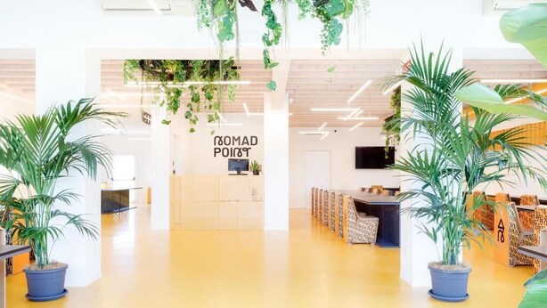 A reception area with a sign reading 'ROMAD POINT,' potted plants, and a seating area with patterned cushions. - Nomad Hostel (Treviso)