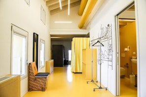 Un pasillo con un banco, un perchero con dibujos y un baño a la vista a través de una puerta abierta.
