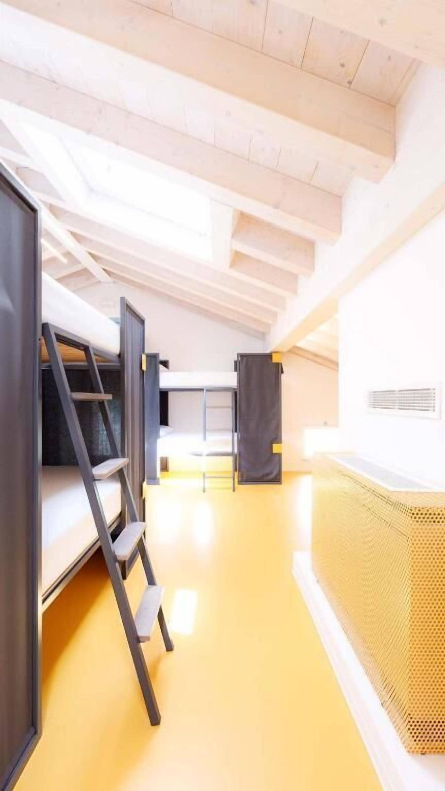 Un intérieur moderne avec des lits superposés, une échelle et un plancher jaune.