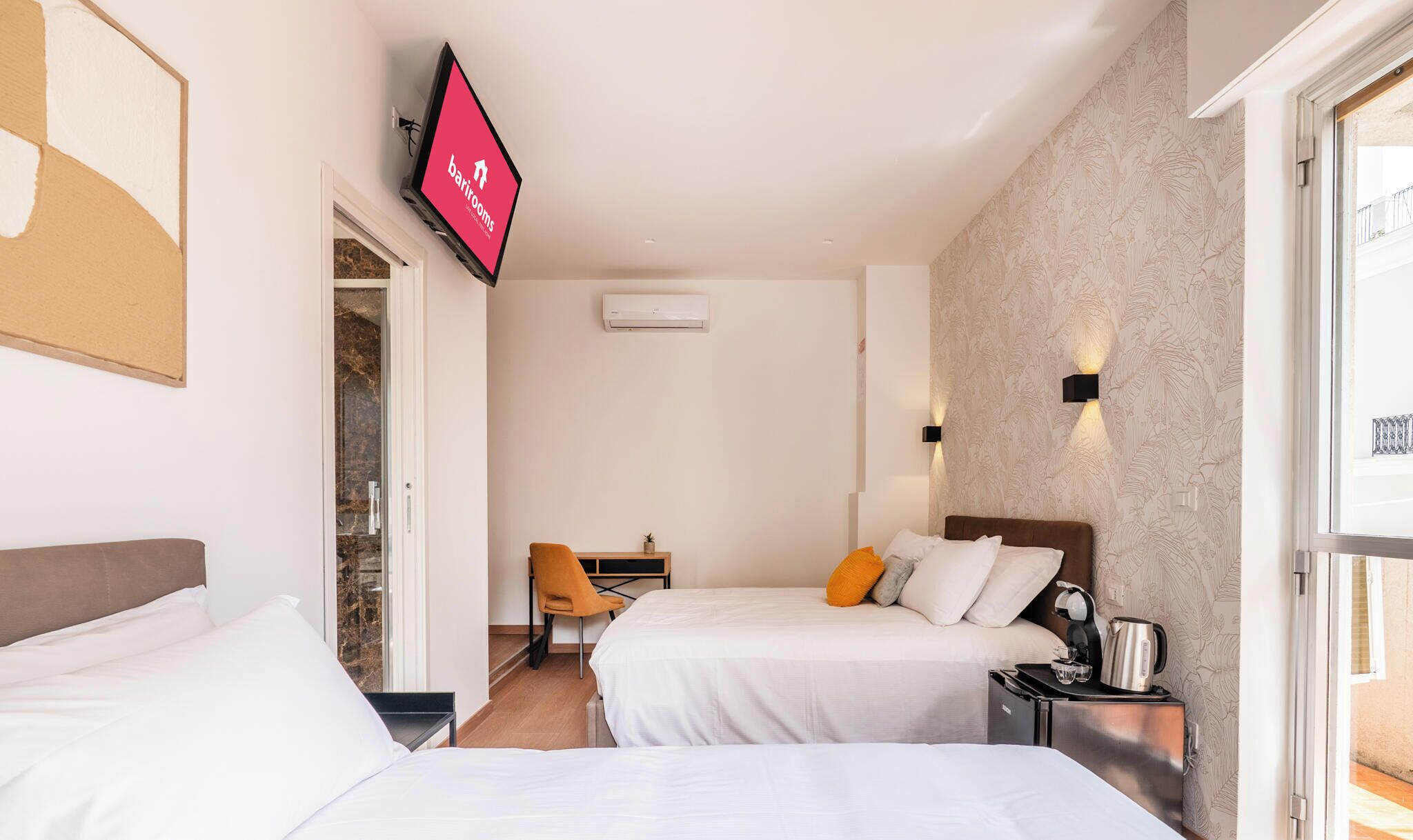 Habitación de hotel con dos camas, un escritorio, una silla, un televisor y un equipo de aire acondicionado.