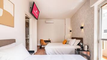 Habitación de hotel con dos camas, un escritorio, una silla, un televisor y un equipo de aire acondicionado.