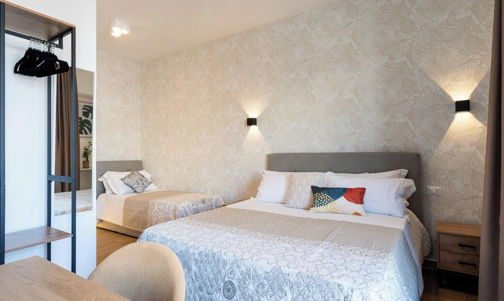 Een hotelkamer met twee bedden, een kast, een bureau en een nachtkastje.