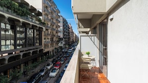 Una calle estrecha en la ciudad, con coches aparcados y un edificio con balcones.