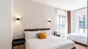 Habitación de hotel con cama, mesitas de noche, cortinas y vistas al exterior.