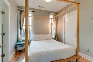 Ein Schlafzimmer mit einem Himmelbett, einem kleinen Nachttisch und Blick durch ein Fenster.