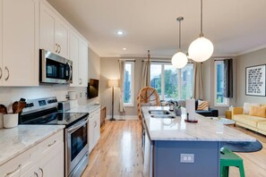 A modern kitchen with white cabinets, a built-in oven, and a large island with a sink. - Rooftop Skyline View-Close to Broadway-Sleeps 8 (Nashville)