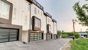Un immeuble à plusieurs étages avec une entrée de garage, une façade en briques et un trottoir dallé.