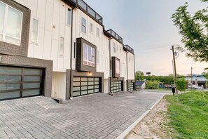 A multi-story building with a garage entrance, brick facade, and a paved walkway. - Rooftop Skyline View-Close to Broadway-Sleeps 8 (Nashville)