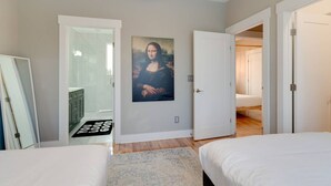 Une chambre à coucher avec un lit, une porte donnant sur une salle de bain et un couloir.