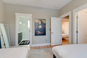 A bedroom with a bed, a door leading to a bathroom, and a hallway.