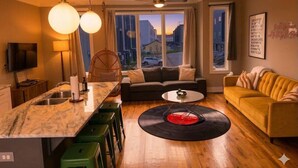 Un salon moderne avec un canapé, une table basse et un présentoir central où sont exposés des disques vinyles.