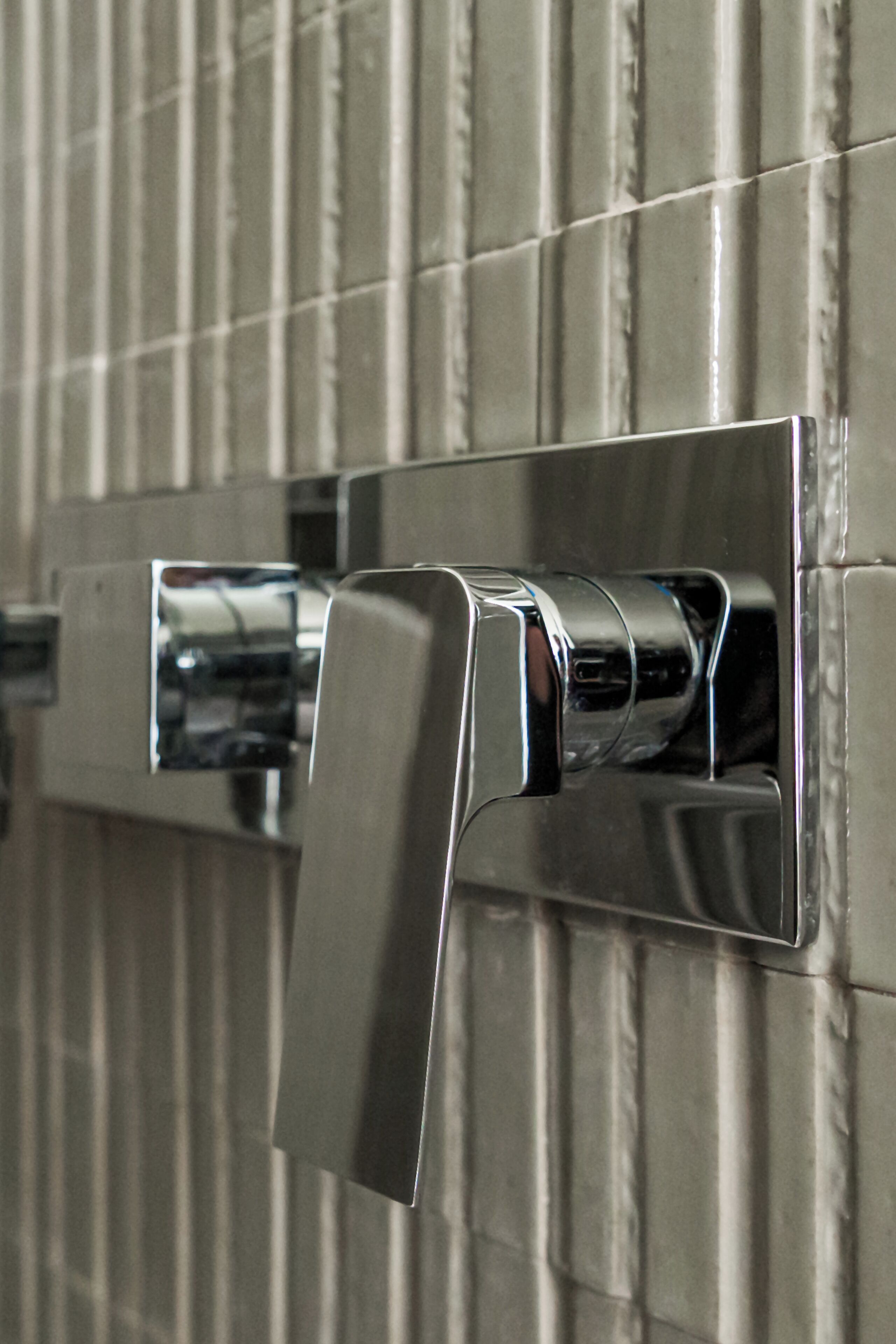 A chrome faucet mounted on a tiled wall.