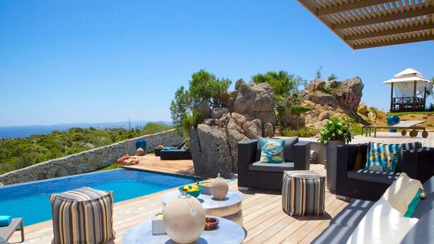 A poolside area with outdoor furniture, a view of the sea, and a rocky landscape. - Villa Carla (Bonifacio)