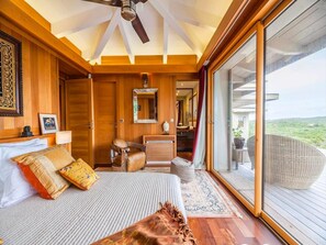 Ein Schlafzimmer mit Bett, Stuhl, Schreibtisch, Spiegel und einem großen Fenster.