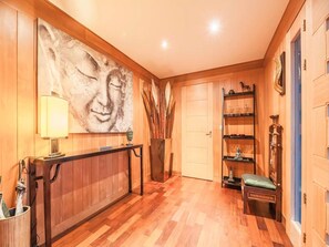 A wooden-floored hallway with a large abstract painting, a desk with a lamp, a bookshelf, and a small meditation area. - Villa Carla (Bonifacio)