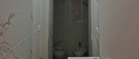 Ein Badezimmer mit Marmorwand, einem Waschbecken und zwei Toiletten.