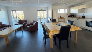 Une cuisine moderne avec des meubles blancs, une cuisinière et un évier. On y trouve également un coin repas avec une table et des chaises en bois, ainsi qu’un banc.