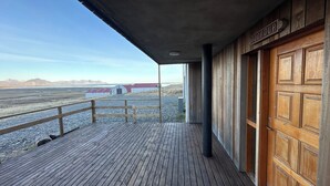 Une terrasse en bois offrant une vue sur un bâtiment aux toits rouges et sur des montagnes au loin.