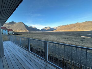 A wooden deck with a metal railing overlooking a mountainous landscape. - Apartment in House in Fjörður in Lón, South East of Iceland (Höfn)