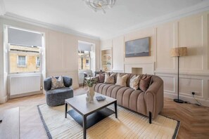 Una sala de estar moderna con sofá, sillón, mesa de centro y chimenea.