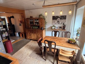 A dining area with a wooden table, chairs, and hanging lights.