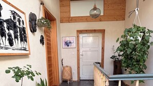 Interior de madeira com escada, porta e diversos vasos de plantas.