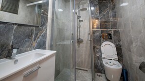 A bathroom with a glass-enclosed shower, a white sink, and a toilet.