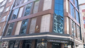 A multi-story hotel with a modern glass facade, large windows, and a prominent logo on the ground floor.