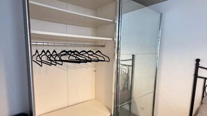 Een kamer met een schuifdeurkast, een bed met metalen frame en een witte muur.