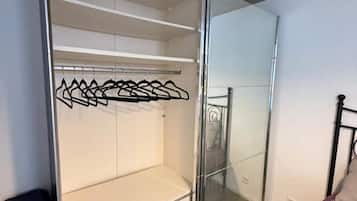 A room with a sliding glass door closet, a bed with a metal frame, and a white wall.