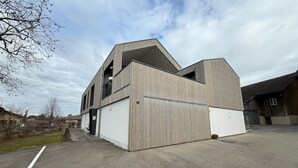 Een modern gebouw met een schuin dak, grote garage deuren en een vlakke entree.