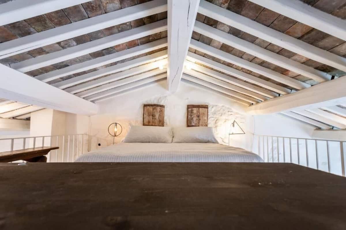 A bedroom with a sloped ceiling, a bed, and two wooden headboards.