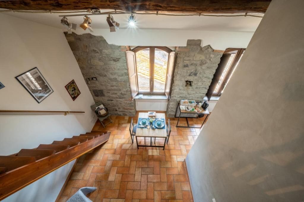 A staircase leading to a dining area with a stone wall, a window, and a table set with plates.