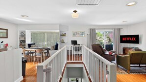 A modern living space with a staircase, a dining area, a seating area, and a television displaying 'NETFLIX'. - Relaxing stay near Louisville's top attractions! (Louisville)