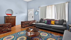 Ein Wohnzimmer mit einer Couch, einem Couchtisch, einer Ziegelwand und einer Tür.
