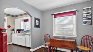 A kitchen with white cabinets, a wooden table, and two red chairs. - Exclusive one-story retreat close to attractions! (Louisville)