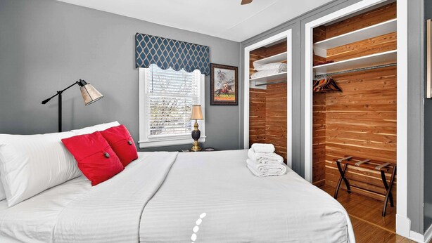A bedroom with a bed, a bedside lamp, a window with blinds, a wooden closet, and a ceiling fan. - Exclusive one-story retreat close to attractions! (Louisville)