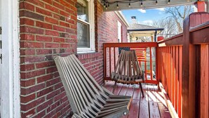 A wooden deck with a red brick wall, a wooden chair, and a wooden fence. - Exclusive one-story retreat close to attractions! (Louisville)