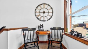 A corner room with a wall clock, two chairs, a small wooden table with figurines, and a window with a view of the street. - Exclusive one-story retreat close to attractions! (Louisville)