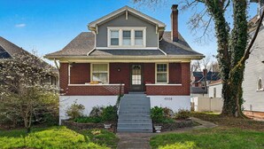 A two-story house with a front porch, a brick facade, and a chimney. - Spacious home w/ yard near Downtown attractions! (Louisville)