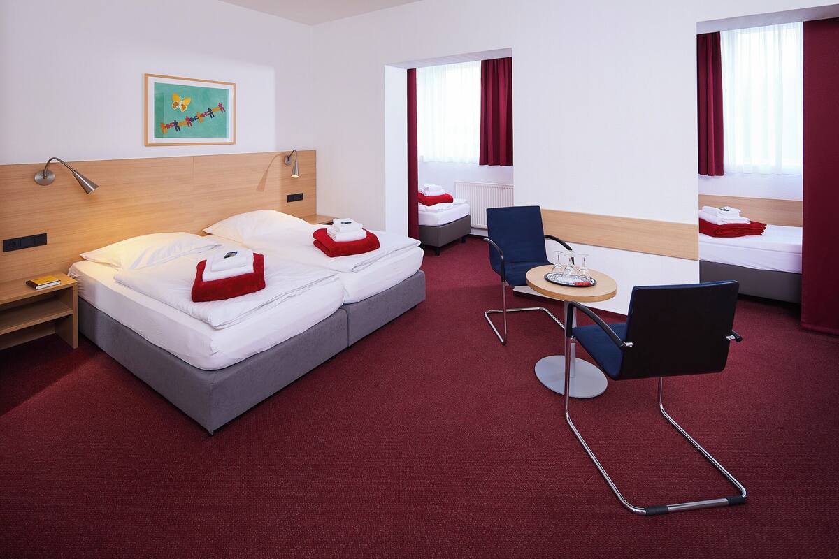 Ein Hotelzimmer mit Bett, Schreibtisch, Stuhl und einem Fenster mit Vorhängen.