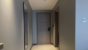 A narrow hallway with a door at the end, a light switch on the wall, and a small sign above the door. - Borrman Hotel Foshan Nanhai Junya Plaza (Foshan)