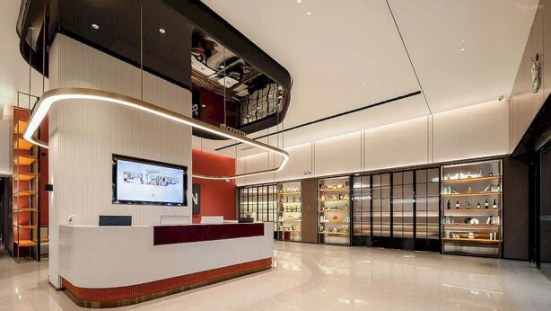 A modern reception area with a flat-screen TV, a reception desk, and a large glass display case with items. - Borrman Hotel Foshan Nanhai Junya Plaza (Foshan)