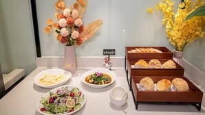 A buffet table with various food items, a small sign, and decorative flowers. - Borrman Hotel Foshan Nanhai Junya Plaza (Foshan)