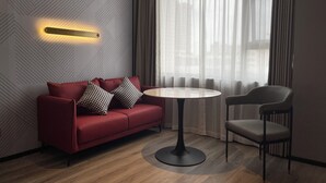 Une pièce moderne avec un canapé rouge, une table ronde et une chaise grise.
