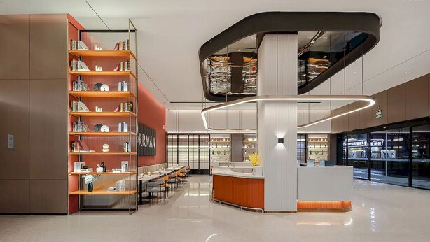 Un intérieur moderne avec un comptoir d’accueil central, une bibliothèque à plusieurs niveaux et un sol propre et bien entretenu.